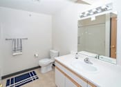 Thumbnail 12 of 14 - A bathroom with a toilet, sink, and mirror.