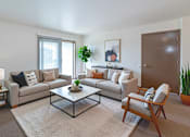 Thumbnail 8 of 14 - A living room with a grey couch, a coffee table, and a wooden chair.