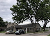 Thumbnail 3 of 12 - a building with two cars parked in front of it