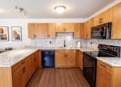 Thumbnail 1 of 14 - A kitchen with wooden cabinets and a granite countertop.