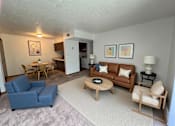 Thumbnail 4 of 13 - A living room with a blue couch, a wooden coffee table, and a lamp.