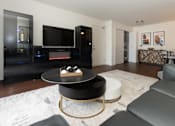 Thumbnail 1 of 17 - A modern living room with a black coffee table and a television.
