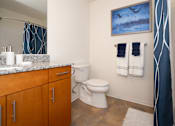 Thumbnail 10 of 17 - A bathroom with a toilet, sink, and a painting on the wall.