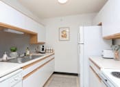 Thumbnail 1 of 11 - A kitchen with white cabinets and a white fridge.