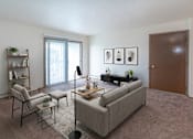 Thumbnail 9 of 11 - A living room with a grey couch, a chair, a small table with a lamp and a potted plant.