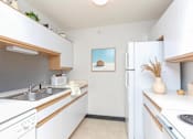 Thumbnail 10 of 13 - A small, clean kitchen with white cabinets and a painting on the wall.