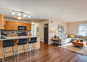 Thumbnail 6 of 8 - A kitchen with a bar area and a living room area.