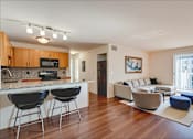 Thumbnail 7 of 8 - A modern kitchen with black chairs and a white countertop.
