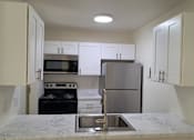 Thumbnail 3 of 8 - A kitchen with a stove, oven, microwave, and refrigerator.