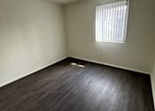 Thumbnail 7 of 8 - A room with a window and wooden flooring.