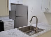 Thumbnail 4 of 8 - A kitchen with a sink and a refrigerator.
