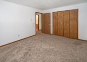 Thumbnail 2 of 11 - an empty living room with a carpeted floor and two closet doors