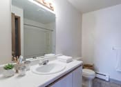 Thumbnail 7 of 11 - A white bathroom with a sink, mirror, toilet and a towel.