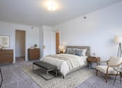 Thumbnail 11 of 11 - A bedroom with a large bed, a chair, and a nightstand.