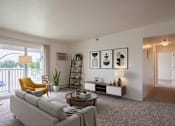 Thumbnail 1 of 11 - A living room with a grey couch, a yellow chair, a coffee table, and a bookshelf.