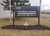 Thumbnail 28 of 33 - A sign for Woodbury Estates Apartments is displayed in front of a building.