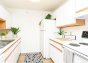 Thumbnail 1 of 14 - A kitchen with white cabinets and a white fridge.