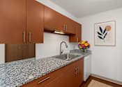 Thumbnail 1 of 20 - A kitchen with brown cabinets and a granite countertop.