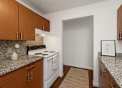 Thumbnail 2 of 20 - A kitchen with a white stove and brown cabinets.