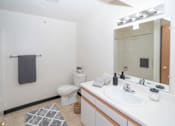 Thumbnail 7 of 10 - A bathroom with a white toilet, sink, and mirror.