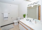 Thumbnail 5 of 14 - A white bathroom with a toilet, sink, mirror, and a plant.