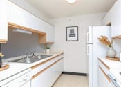 Thumbnail 8 of 14 - A kitchen with white cabinets and a fridge.