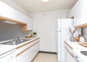 Thumbnail 3 of 14 - A kitchen with white cabinets and a white refrigerator.