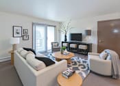 Thumbnail 6 of 14 - A living room with a white sofa, a wooden coffee table, and a grey armchair.
