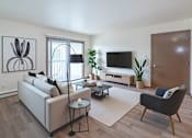 Thumbnail 1 of 14 - A living room with a white sofa, a black chair, a coffee table, a television, and a plant.