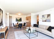 Thumbnail 2 of 14 - A modern living room with a white couch and a glass coffee table.
