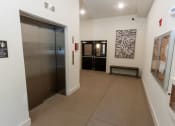 Thumbnail 29 of 35 - a hallway with a door to a elevator and paintings on the wall