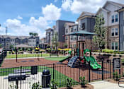 Thumbnail 25 of 25 - A playground with a green slide and a black fence.