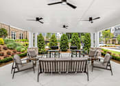 Thumbnail 21 of 31 - A patio with a table and chairs under a white roof.