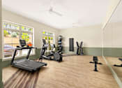 Thumbnail 16 of 31 - A room with a treadmill, exercise bike, and other workout equipment.