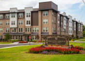 Thumbnail 1 of 40 - an apartment building with a sign in front of a lawn and flowers