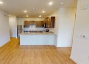 Thumbnail 13 of 25 - A kitchen with wooden floors and white walls.