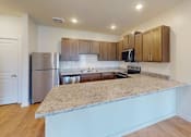 Thumbnail 14 of 25 - A kitchen with a granite countertop and wooden cabinets.