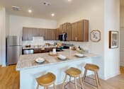 Thumbnail 9 of 25 - A kitchen with a marble countertop and wooden bar stools.