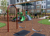 Thumbnail 20 of 25 - A playground with a green slide and a brown swing set.