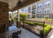 Thumbnail 24 of 40 - a patio with a table and two chairs and an apartment building in the background