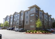 Thumbnail 38 of 40 - a large apartment building with a parking lot in front of it
