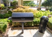 Thumbnail 28 of 40 - a charcoal grill and a trash can sit in front of a garden