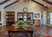 Thumbnail 12 of 14 - A living room with a wooden coffee table and a large chandelier.