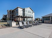 Thumbnail 2 of 14 - A row of lounge chairs are set up on a patio in front of a building.