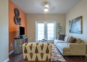 Thumbnail 4 of 14 - A living room with a couch, a chair, a television, and a ceiling fan.