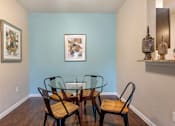 Thumbnail 6 of 14 - A dining room with a glass table and chairs.