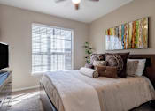 Thumbnail 9 of 14 - A bedroom with a bed, a television, and a painting on the wall.