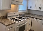 Thumbnail 1 of 18 - Kitchen with white cabinets and a stove and a sink at Brookwood at Bay Shore in Bay Shore, NY 11706