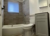 Thumbnail 2 of 18 - Bathroom with a toilet and a tub and a sink at Brookwood at Bay Shore in Bay Shore, NY 11706