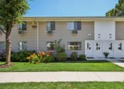 Thumbnail 20 of 37 - Exterior view of apartment building with green grass and trees at Brookwood at Ridge, New York, 11961